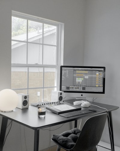 白色木桌上的黑色平板电脑显示器

